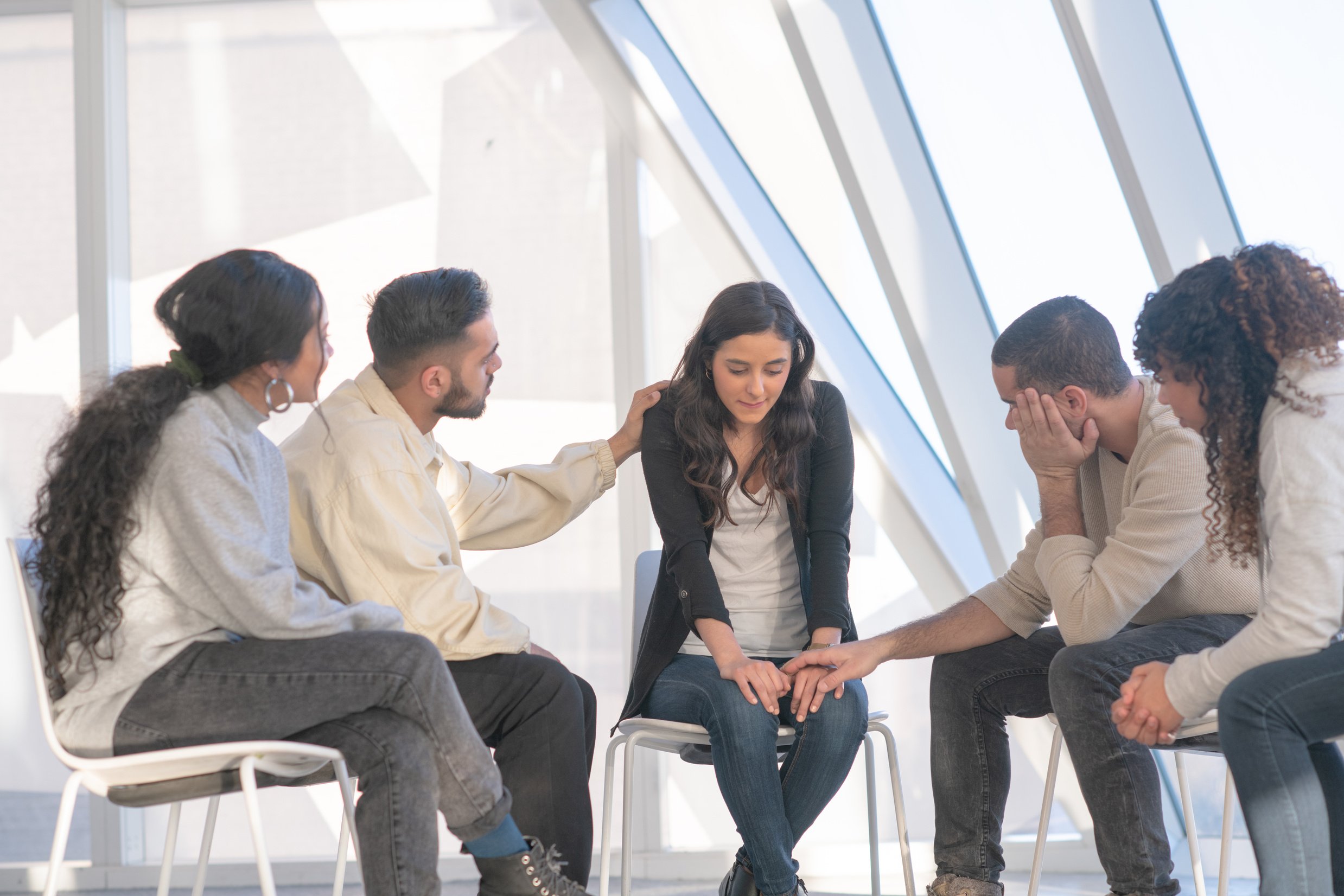 Young adults consoling a friend in group therapy