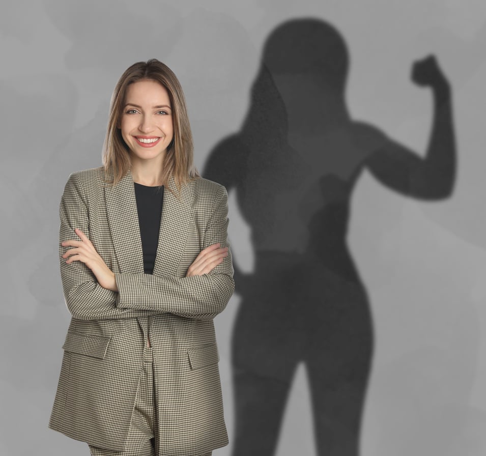 Businesswoman and Shadow of Strong Muscular Lady behind Her on Grey Wall. Concept of Inner Strength