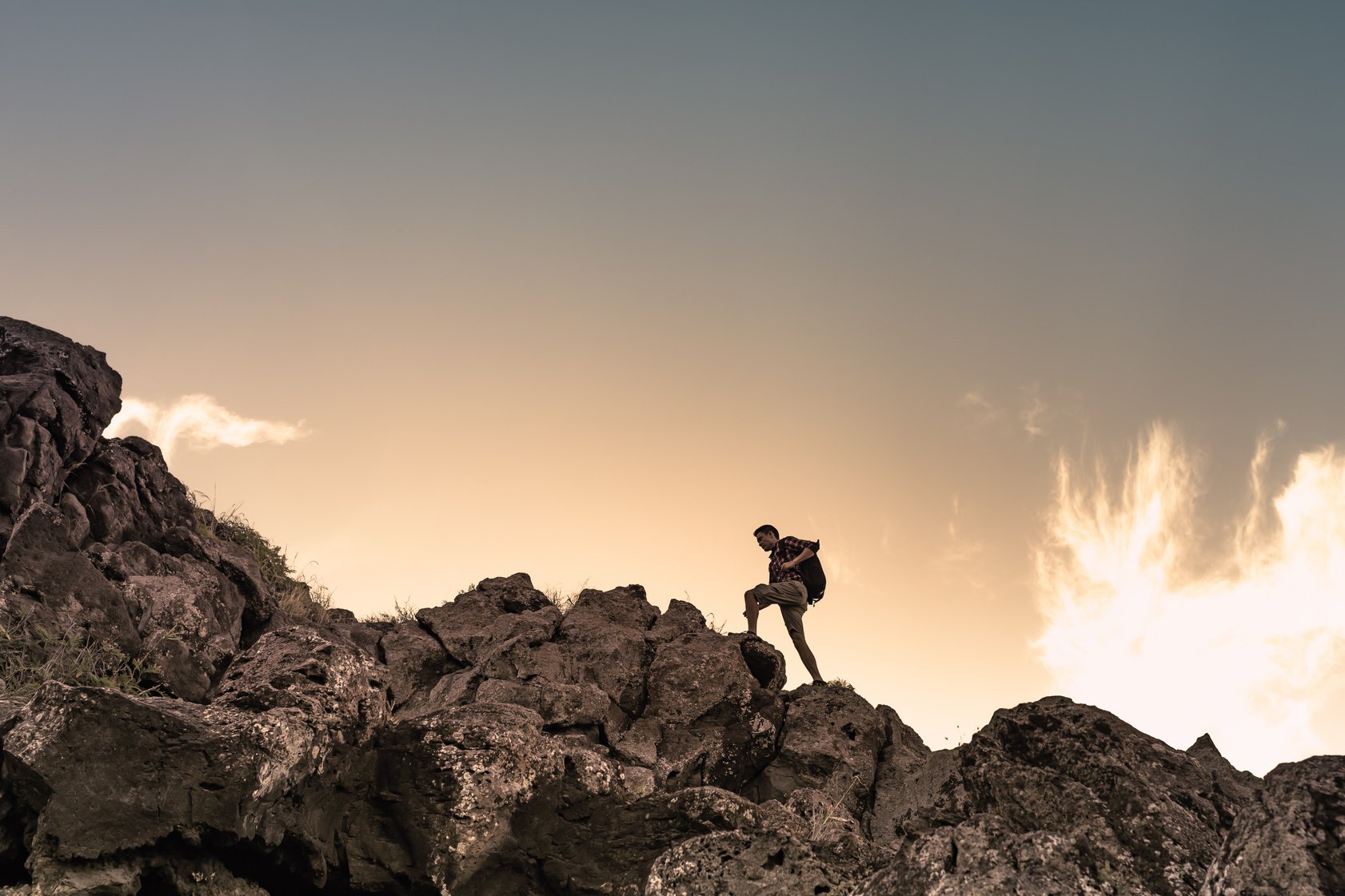 Male hiker hiking climbing  up a rocky mountain. Self improvement and setting goals concept.